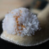 detailfoto van een witte pompon met gouddraad