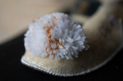 detailfoto van een witte pompon met gouddraad