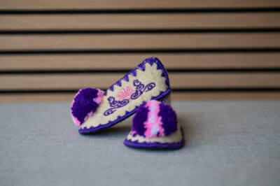 Babysloffen Griekse wollen slof maat 18 Griekse wollen babysloffen maat 18 wit paars met kleurrijke pompon. 100 % schapenwol en authentiek Grieks.